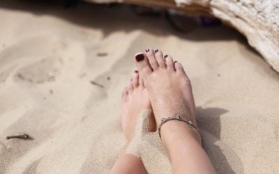 Grounding and earthing feet on sand at the beach.