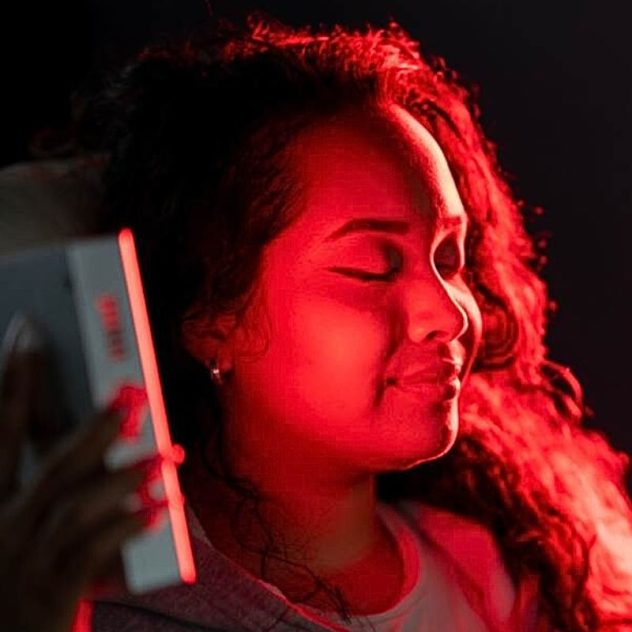Red light therapy and infrared mini panel used by women on face.