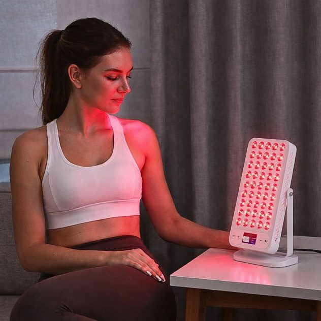 Woman using the PowerPro red light therapy panel for facial rejuvenation.