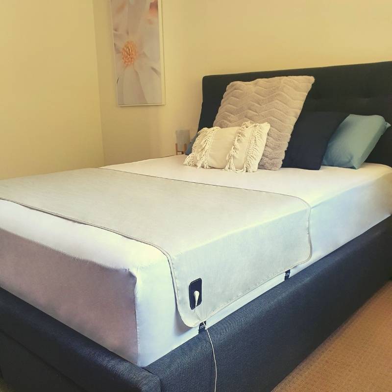 Single size grounding sheet installed on a bed and plugged in.