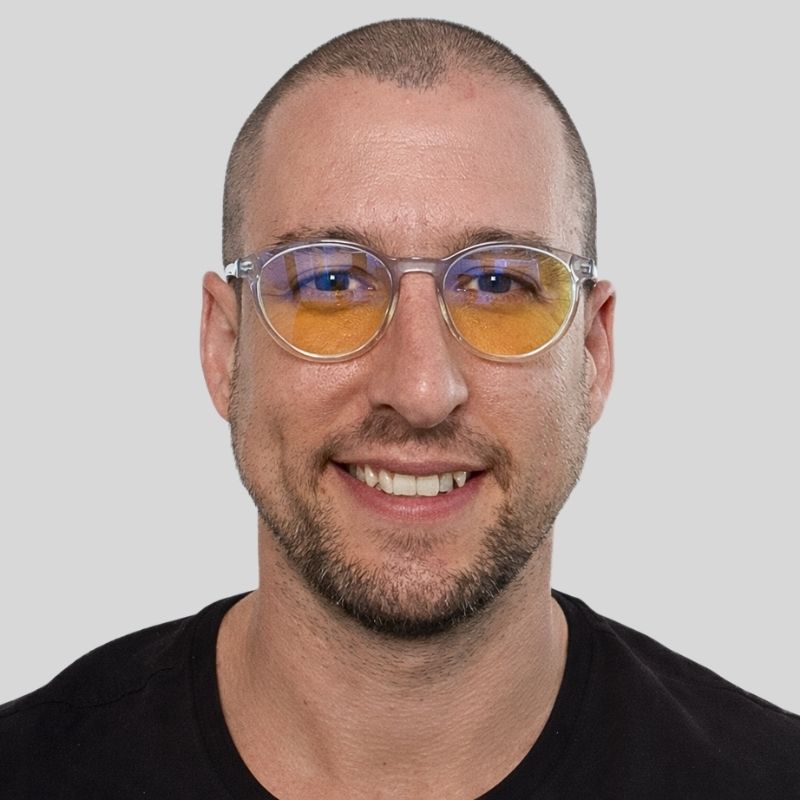 Man wearing clear frame blue light blocking glasses with yellow lenses, shown in a sharp front-facing studio portrait. Man wearing clear frame blue light blocking glasses with yellow lenses, shown in a sharp front-facing studio portrait.