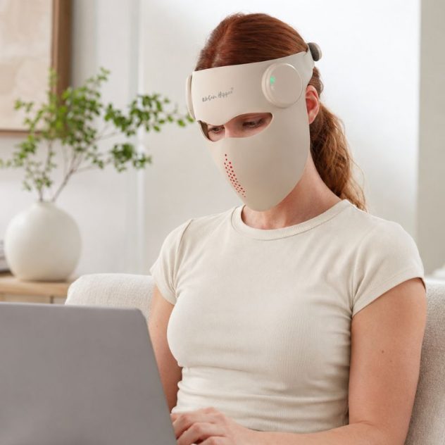Woman wearing an Urban Hippee red light therapy face mask while relaxing at home.