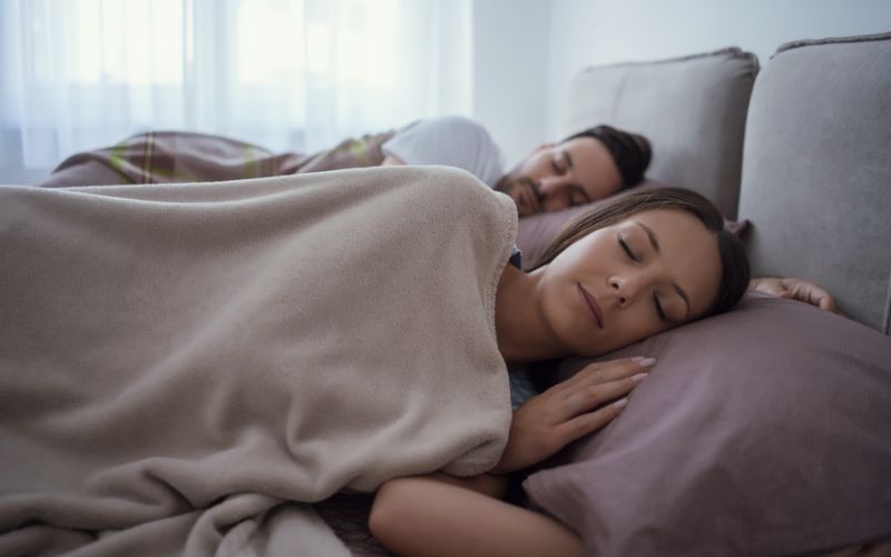 Couple sleeping on earthing & grounding sheet premium underlay. .