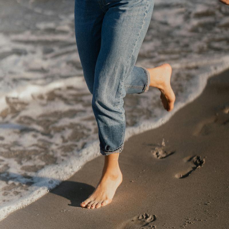 Young girl running on the beach for grounding benefits. 