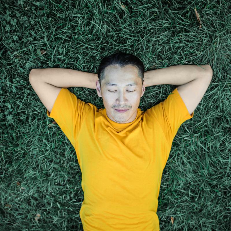 Man relaxing on the grass grounding (earthing) his body. 