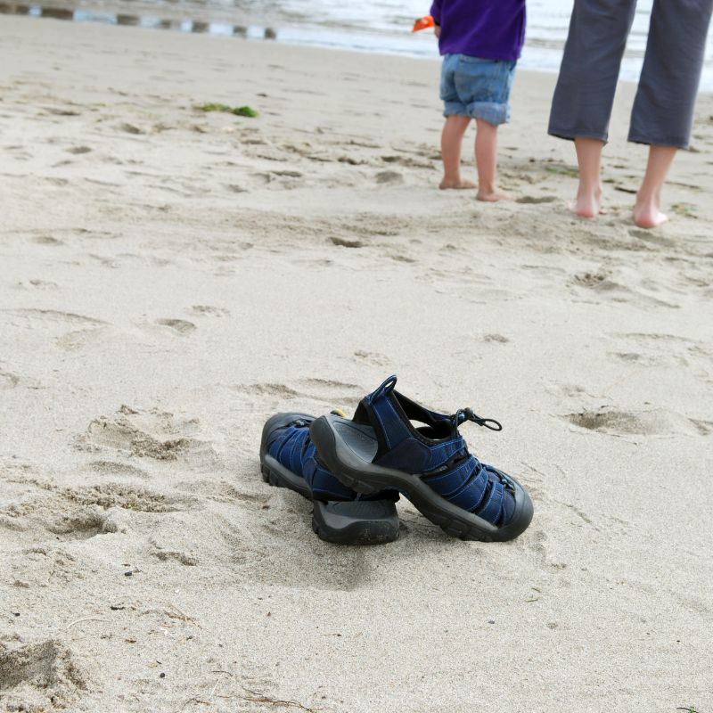 Young kid without shoes on beach grounding themselves with their mum.
