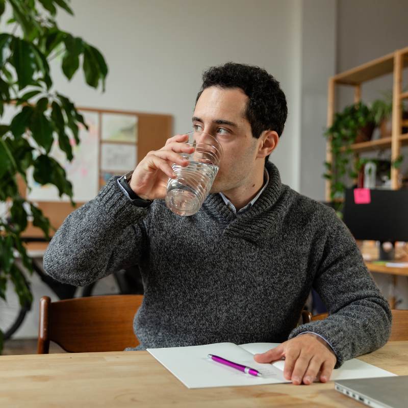 Man drinking glass of water to promote better earthing and grounding results from mat.