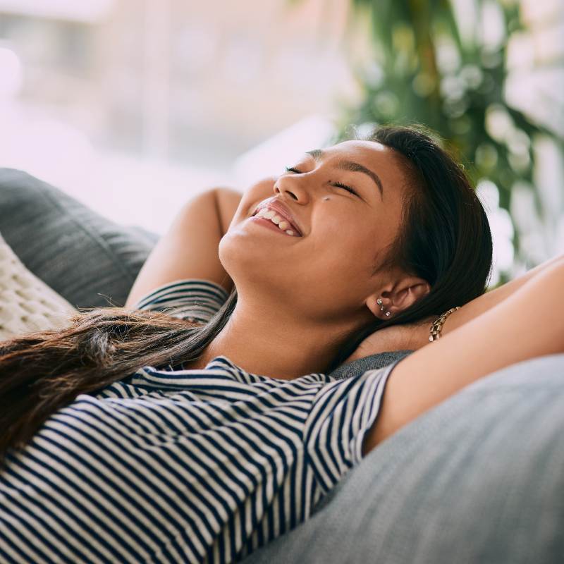 Girl using grounding and earthing mat on couch.