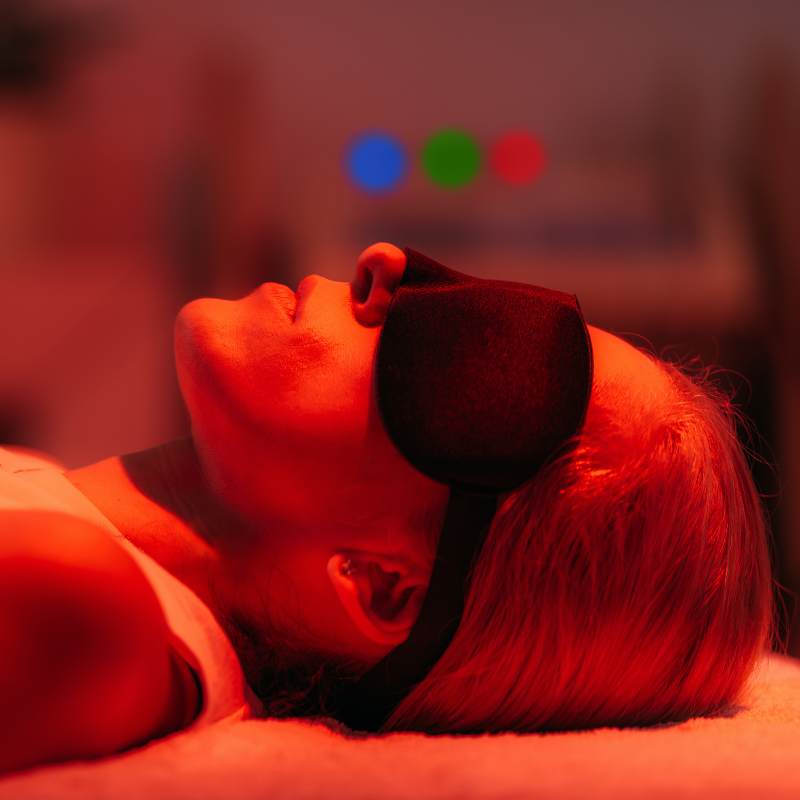 Lady laying down receiving red light therapy and infrared therapy treatment. 