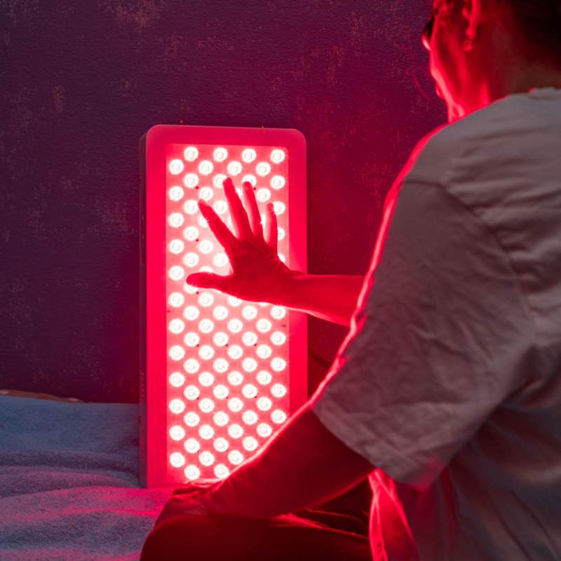 Women touching her red light therapy and inrared panel with hand. 