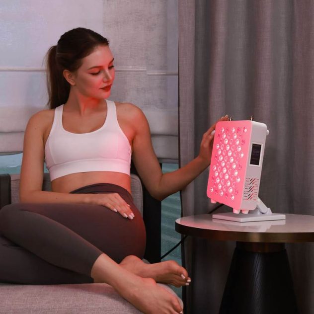 Lady sitting on chair using red light therapy and infrared panel.