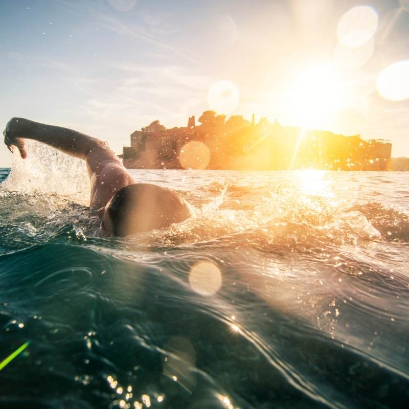 Man swimming in seawater enjoying full-body grounding benefits at the beach
