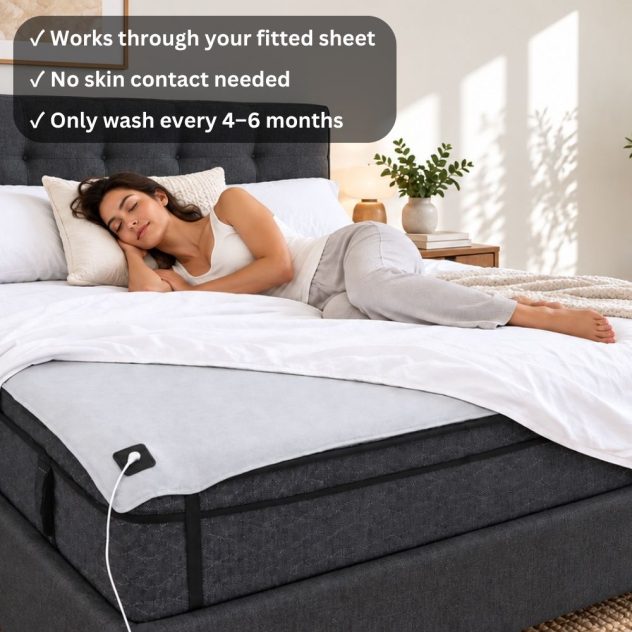 Woman relaxing in bed with Urban Hippee Premium Grounding sheet beneath the fitted sheet, showing the grounding cord and connector.