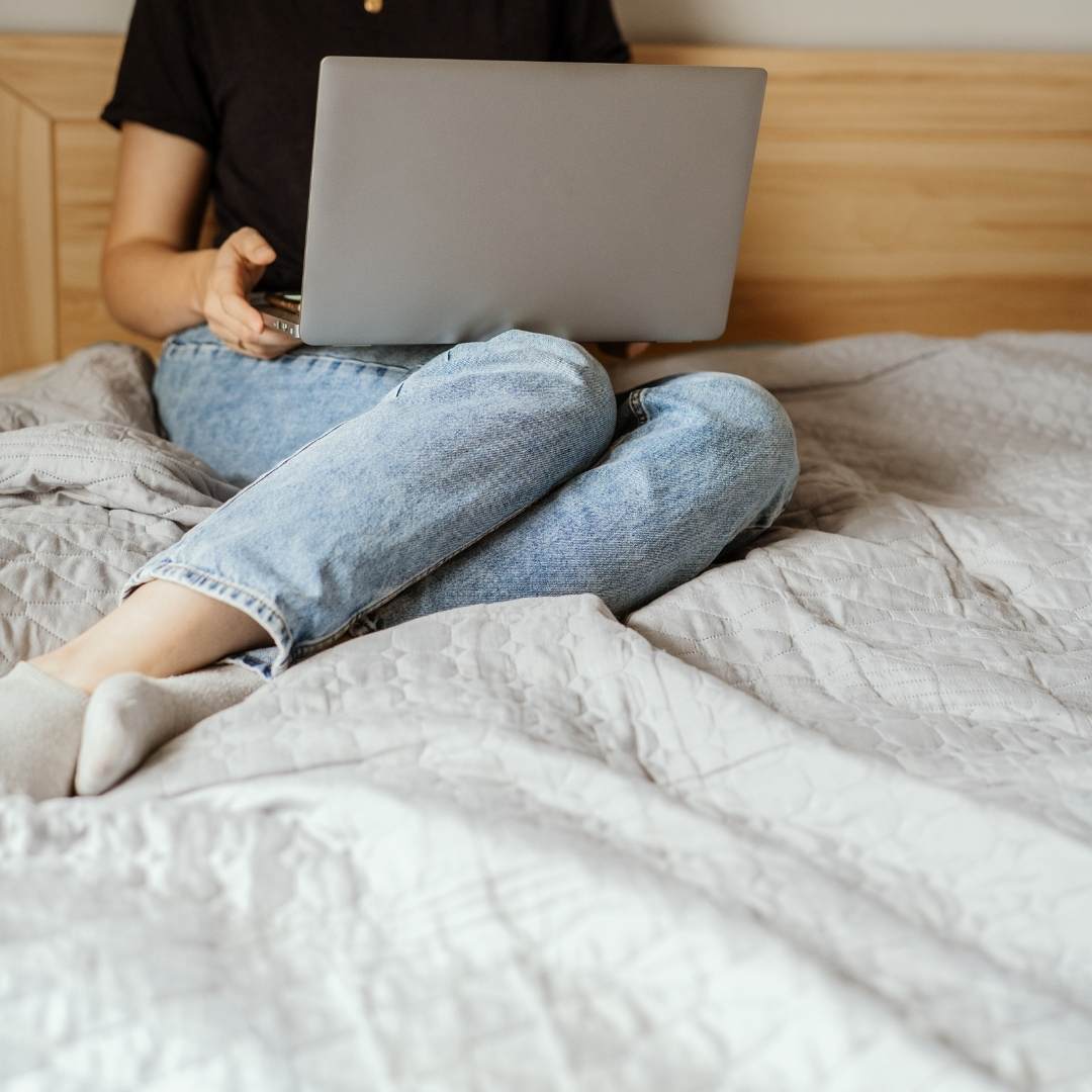Lady sitting on grounding sheet using laptop.