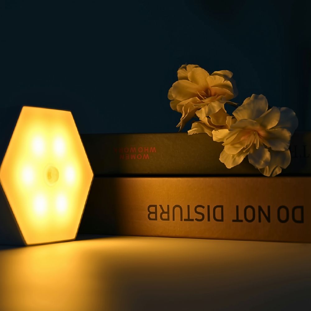 SleepGlow amber motion light glowing beside a bedside table for soft night-time illumination. SleepGlow amber motion light glowing beside a bedside table for soft night-time illumination.